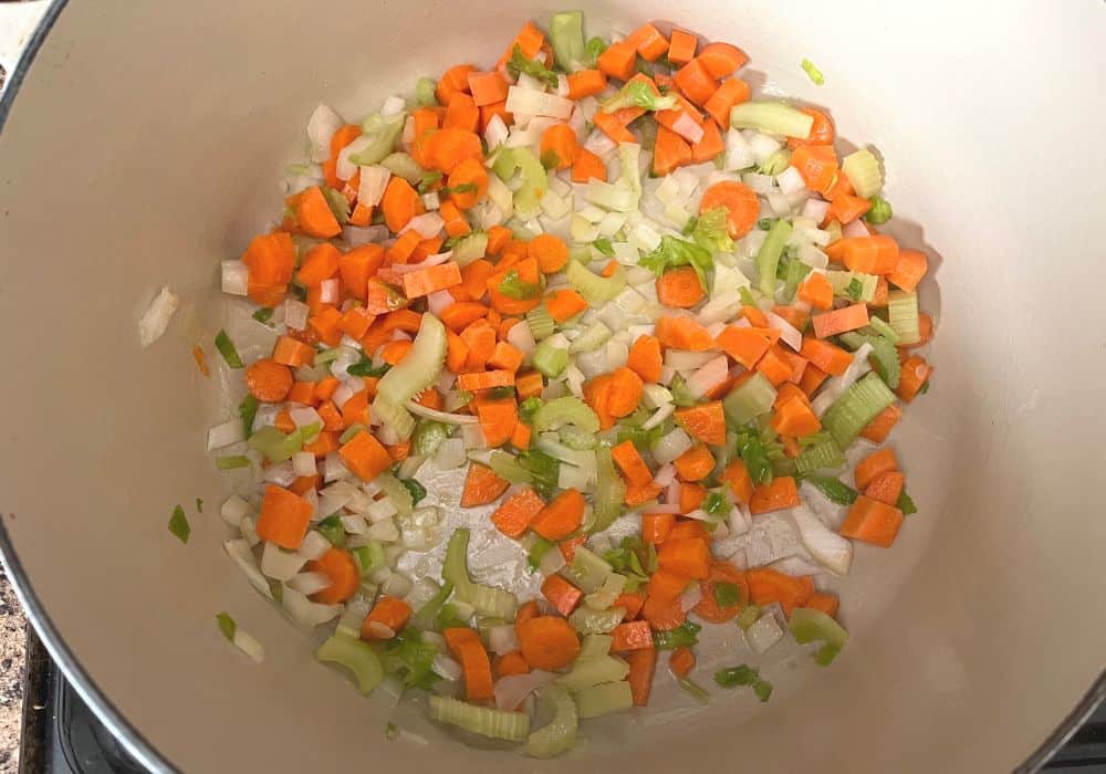 vegetables being sauteed in a dutch oven