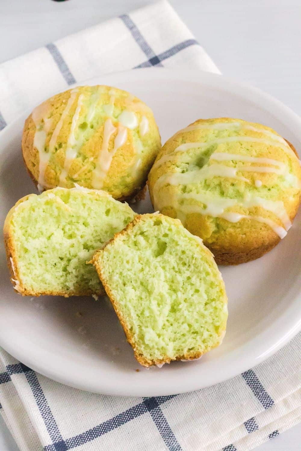 close-up view of pistachio muffins served on a white plate. The muffins are drizzled with glaze.