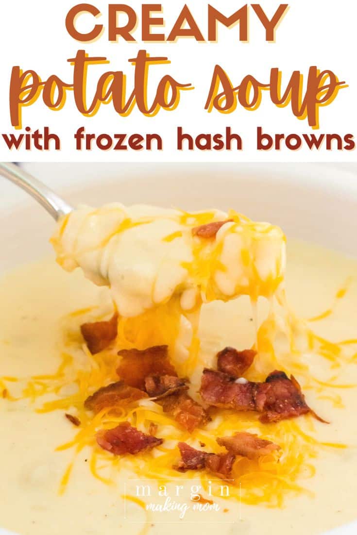 a spoon lifts out a bite of hash brown potato soup, with melted cheese and bacon bits on top.