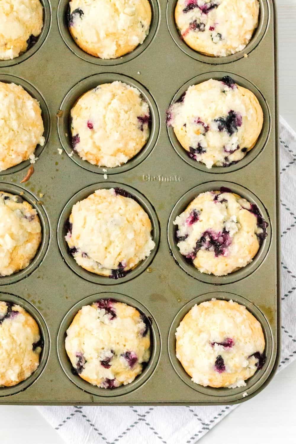 freshly baked blueberry bisquick streusel muffins in a muffin tin