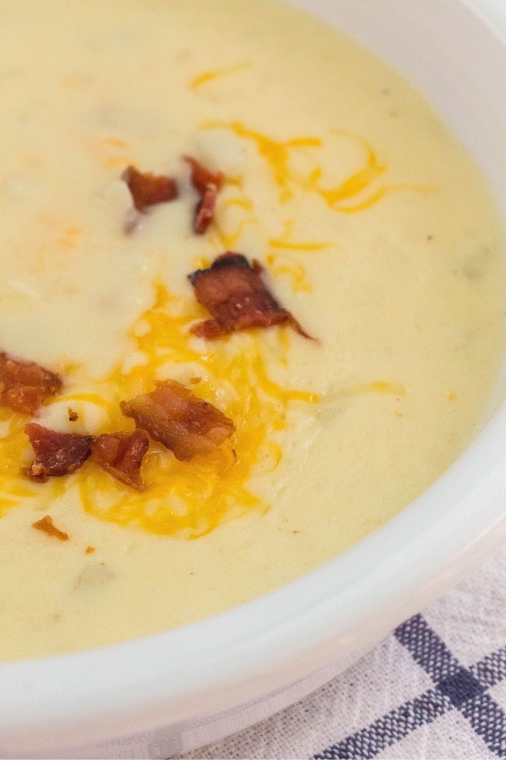 close-up view of creamy hashbrown potato soup topped with crumbled bacon and shredded cheese