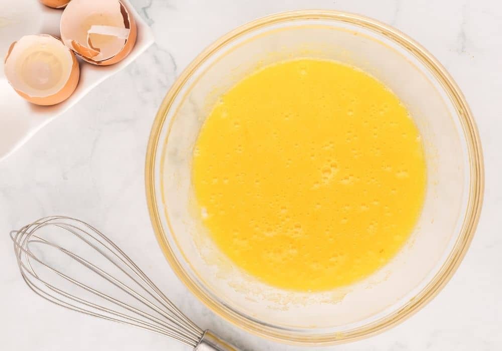 sugar and eggs whisked together in a glass mixing bowl
