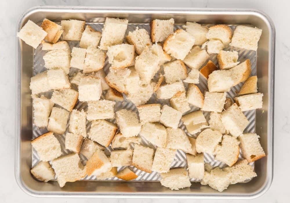 cubed bread on a baking sheet, ready to be toasted