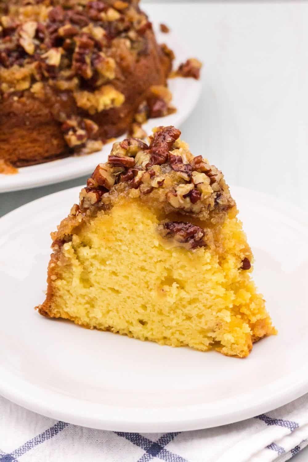 slice of cake mix pecan upside down cake served on a white plate in front of the remaining bundt cake