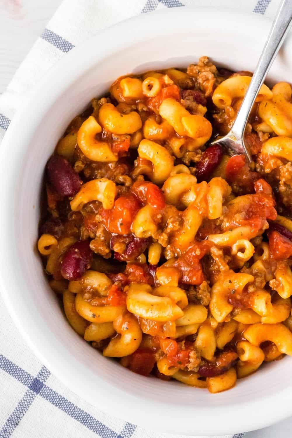 a spoon scoops out a bite of Instant Pot chili mac from a white bowl