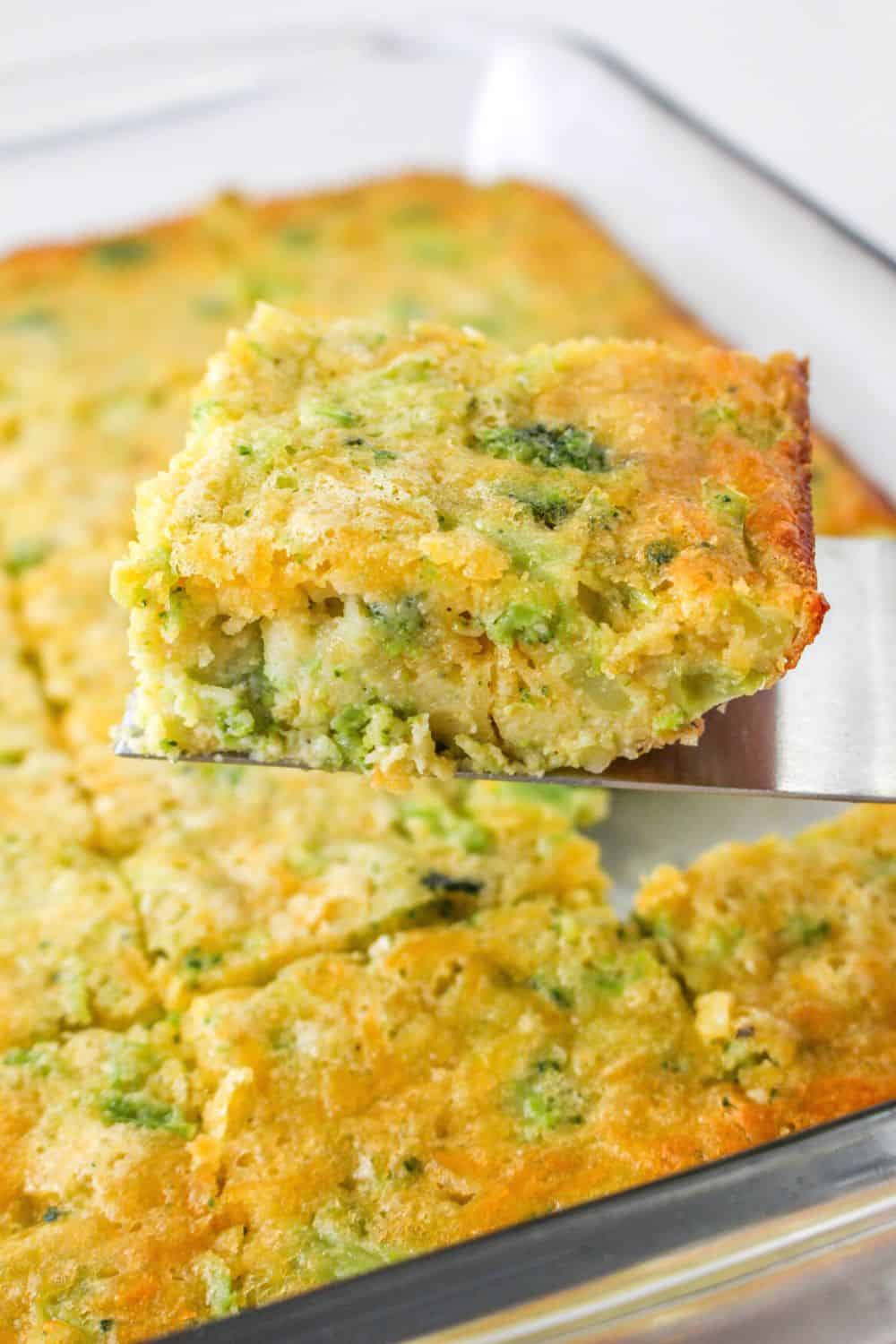 a spatula lifts out a slice of cheesy broccoli cornbread from the pan