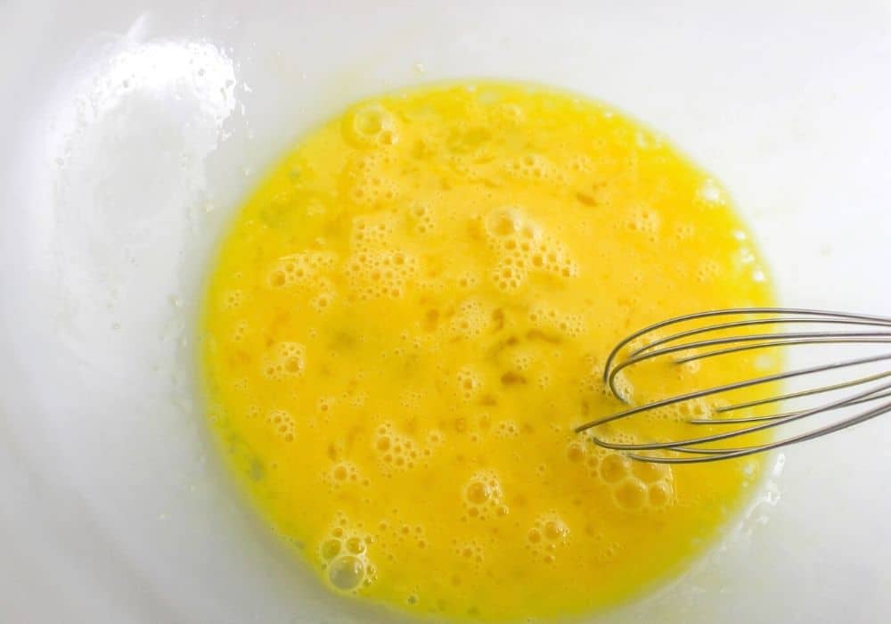 eggs being whisked in a glass mixing bowl