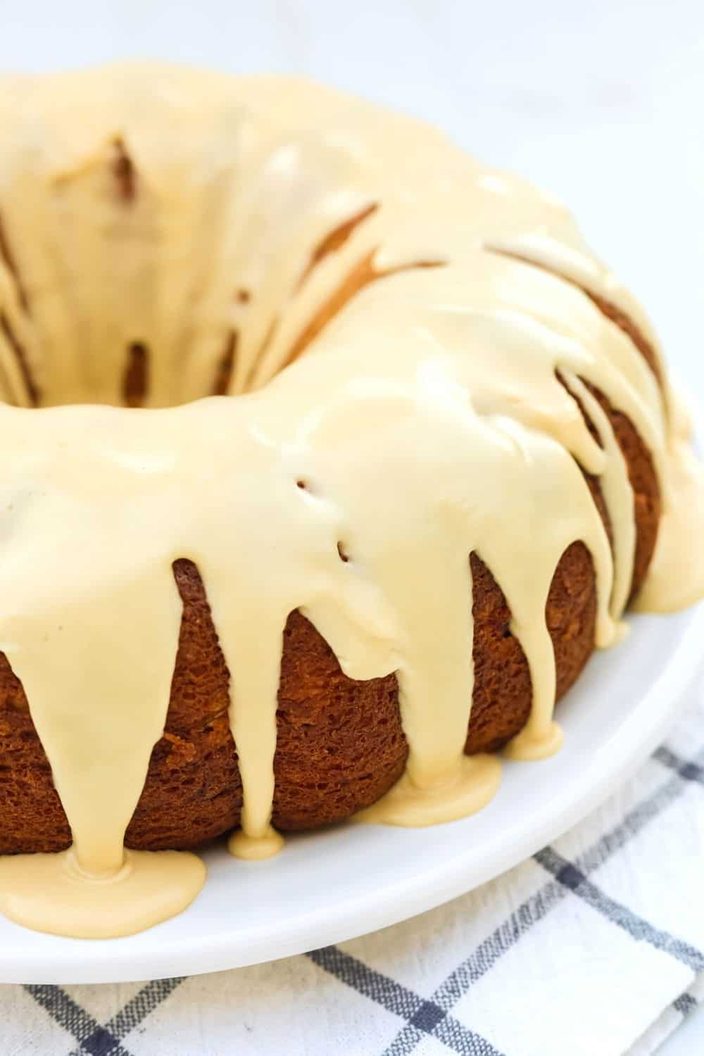 side view of a pear bundt cake made with a cake mix, on a white serving platter. The bundt cake is drizzled with a brown sugar icing.