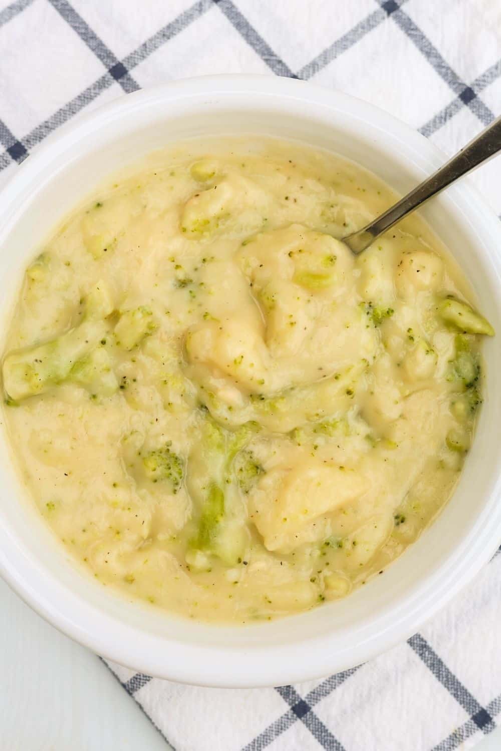 bowl of chunky potato broccoli cheese soup with a spoon in it.