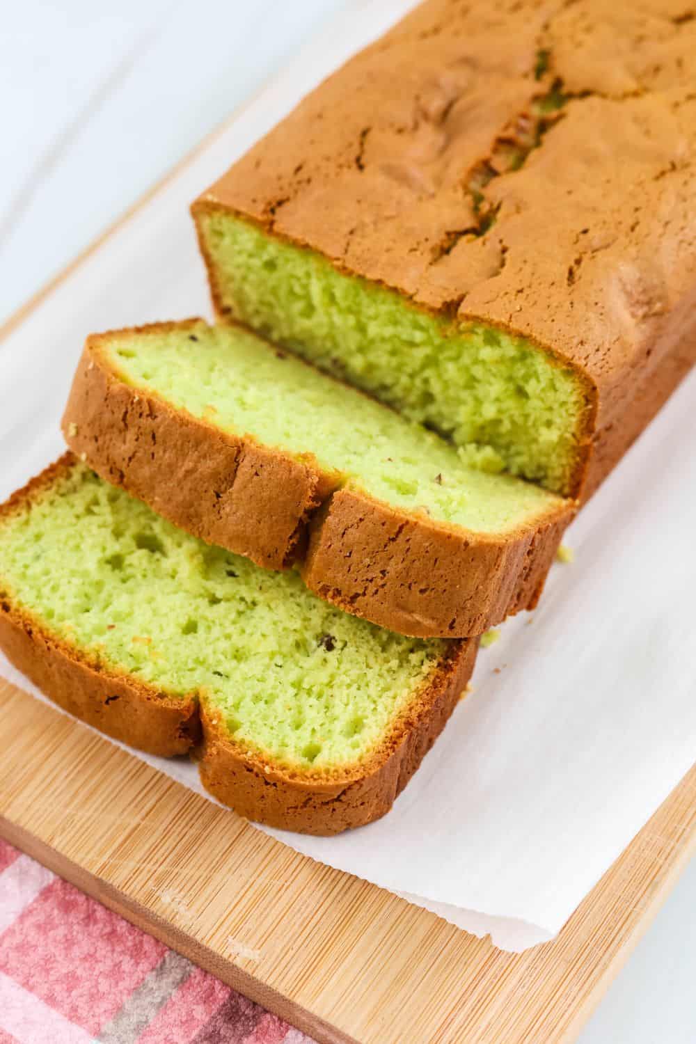 a sliced loaf of pistachio bread made with cake mix on a parchment-lined cutting board
