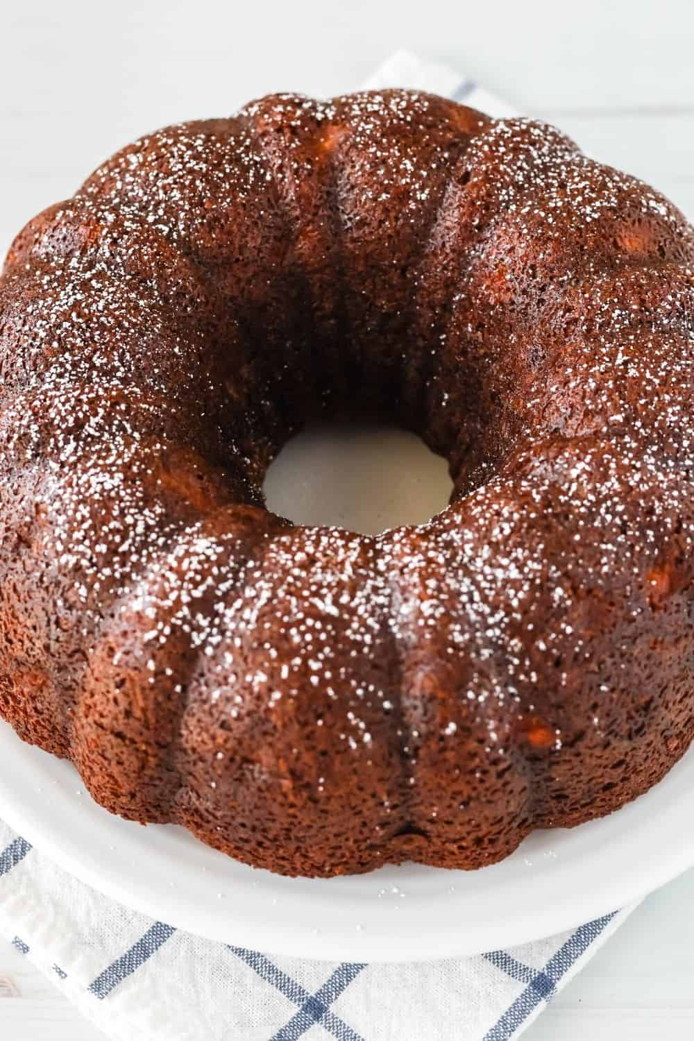 whole bundt cake made with bananas and pears, dusted with powdered sugar and served on a white platter.