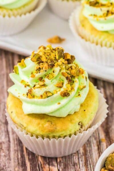 close-up view of pistachio cupcakes made with cake mix and pudding mix, topped with buttercream and chopped nuts.