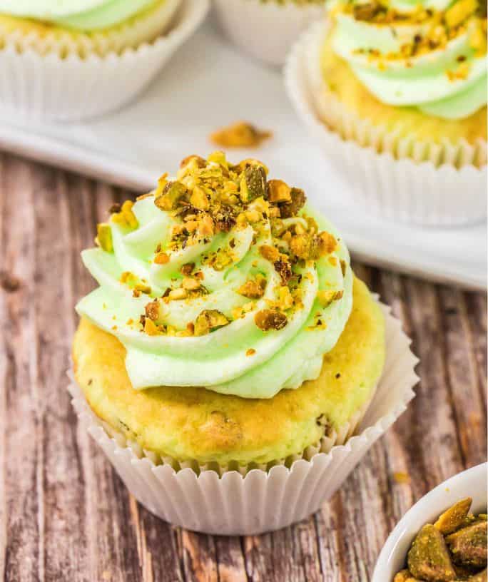 close-up view of pistachio cupcakes made with cake mix and pudding mix, topped with buttercream and chopped nuts.