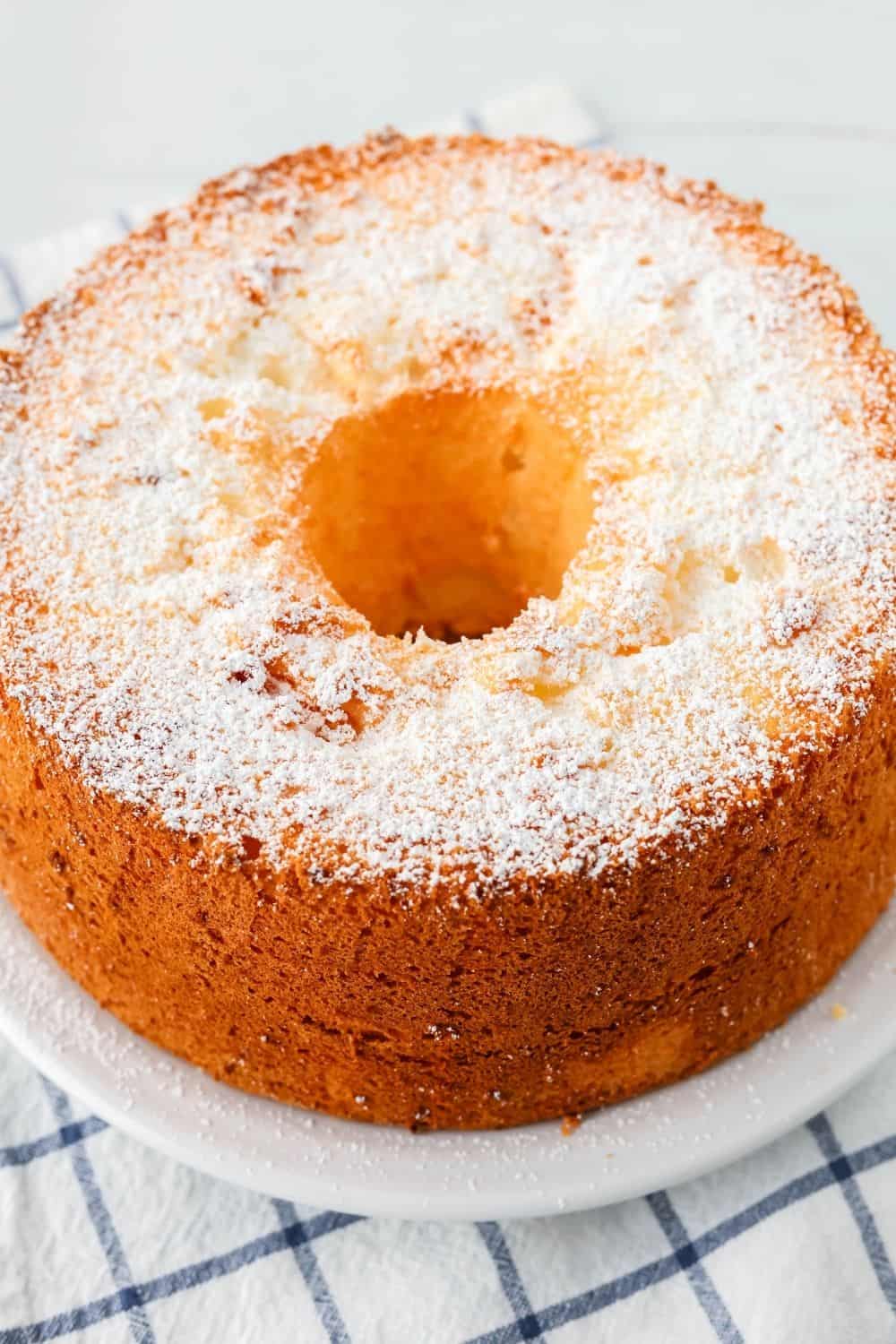 whole angel food cake made from a cake mix, served on a white plate and dusted with powdered sugar.