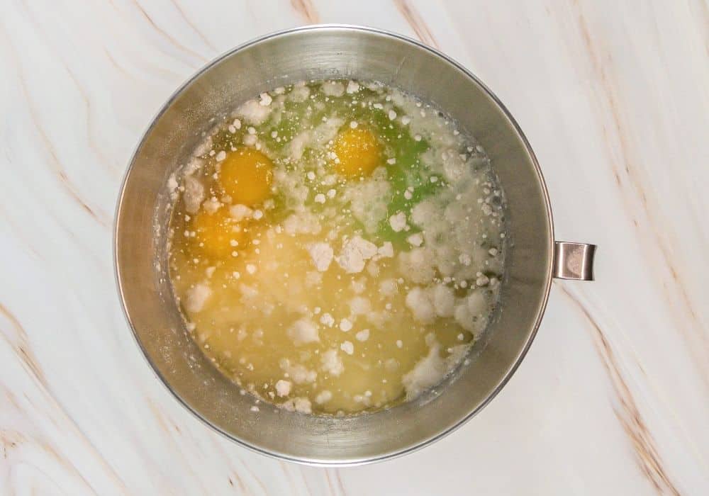 a mixing bowl containing cake mix, oil, water, eggs, pudding mix, and almond extract.