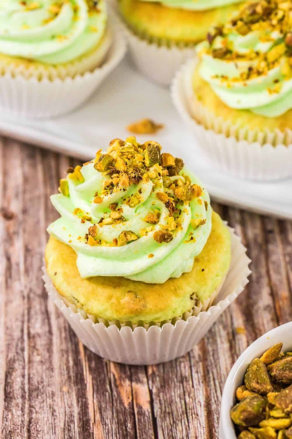 pale green pistachio cupcake made from cake mix, topped with pistachio pudding buttercream and garnished with chopped nuts.