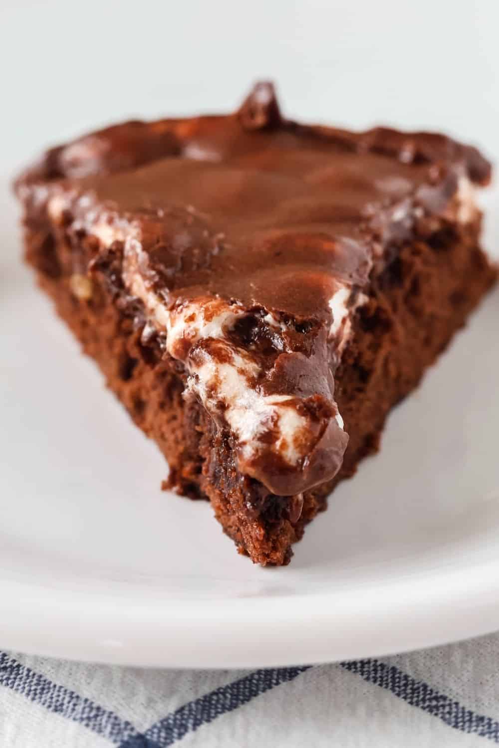 close-up view of a wedge slice of appalachian brownie fudge pie, showing melted marshmallows and chocolate icing over the brownie layer.