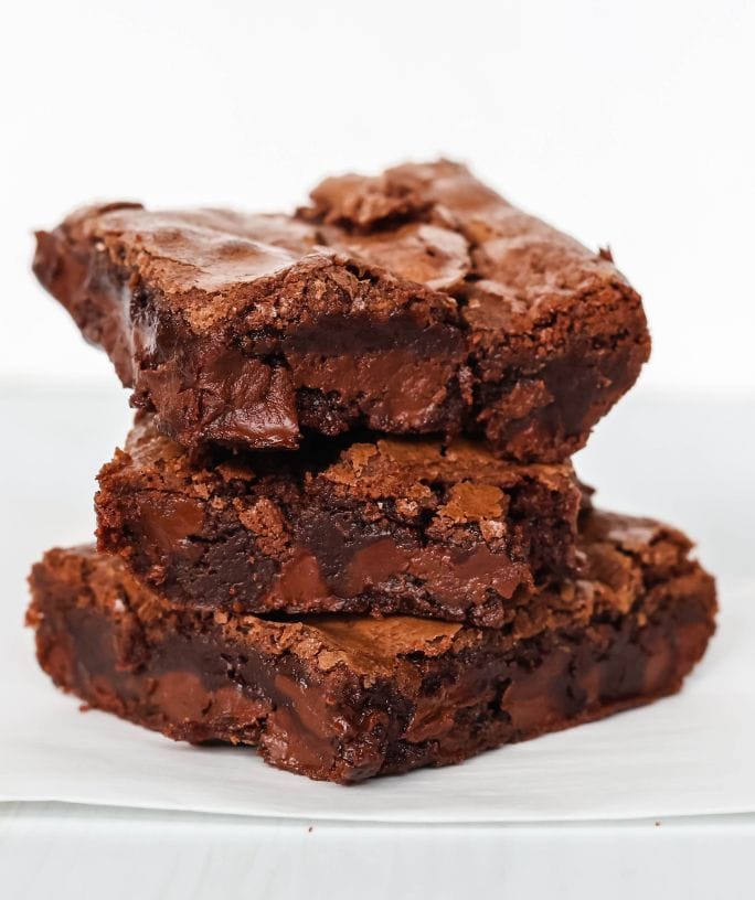 three Bisquick brownies stacked on top of each other on a piece of parchment paper