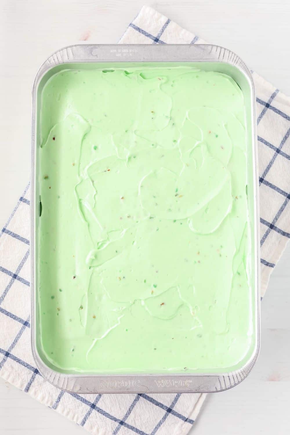 overhead view of a frosted pistachio sheet cake in an aluminum pan.