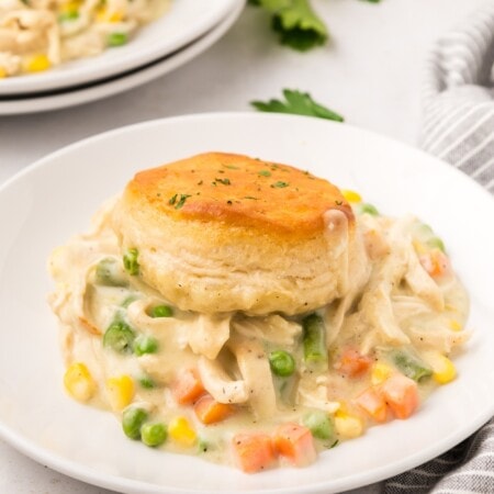 Chicken pot pie with biscuits served on a white plate.