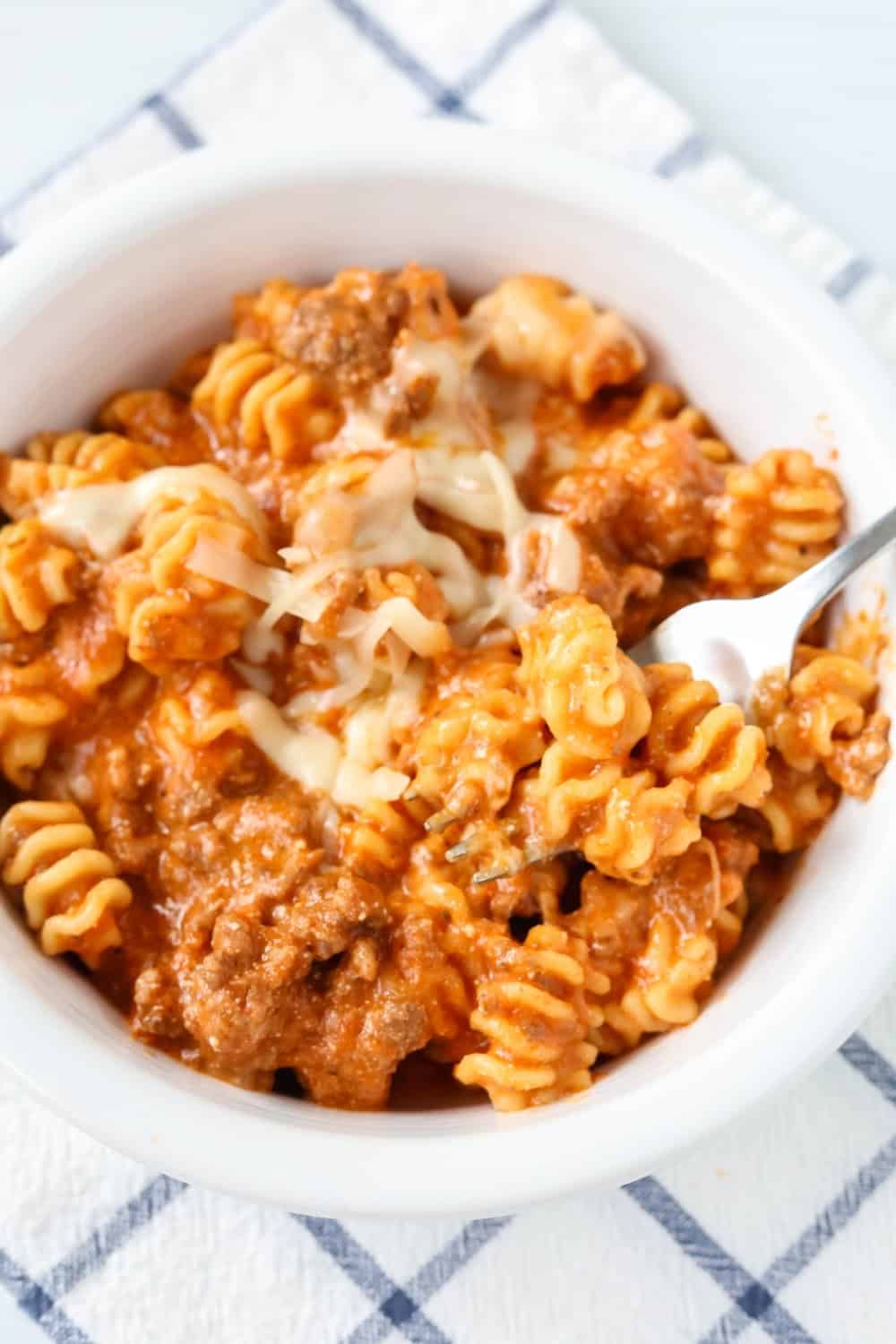 a white bowl serves lazy lasagna cooked in the Instant Pot. A fork is in the dish.