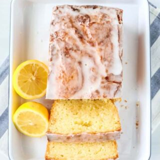 overhead view of a lemon curd loaf cake on a white platter, with a couple of slices cut from it.