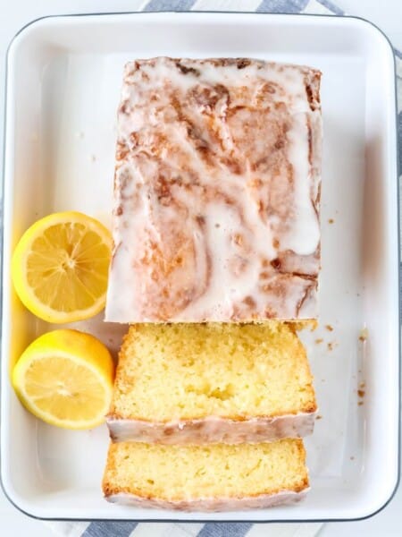 overhead view of a lemon curd loaf cake on a white platter, with a couple of slices cut from it.