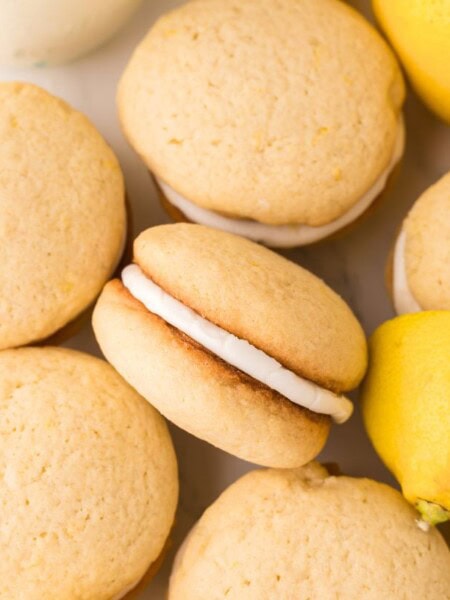 several lemon whoopie pies next to each other, with one turned on its side to show the delicious filling in the sandwich cookie.