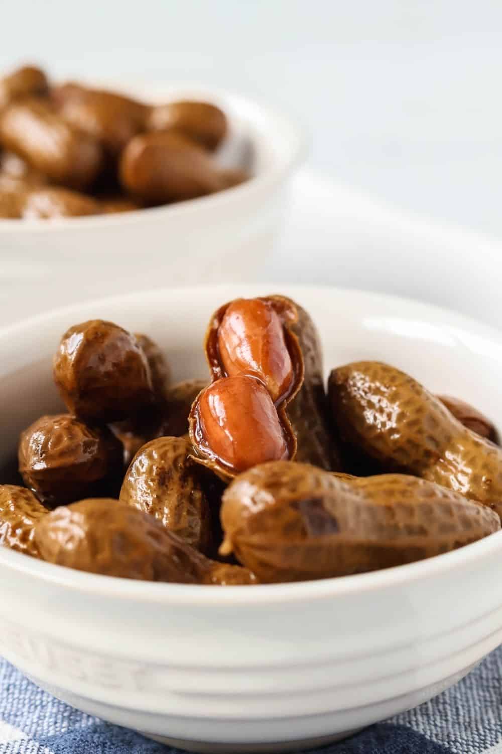 close-up view of spicy boiled peanuts made with Nashville Hot seasoning, served in white bowls.