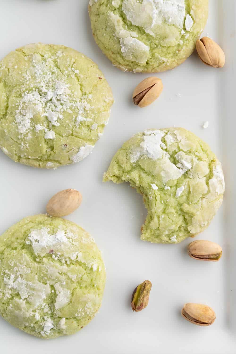 overhead view of four Jello pistachio pudding cookies on a plate. One cookie has a bite taken out of it.