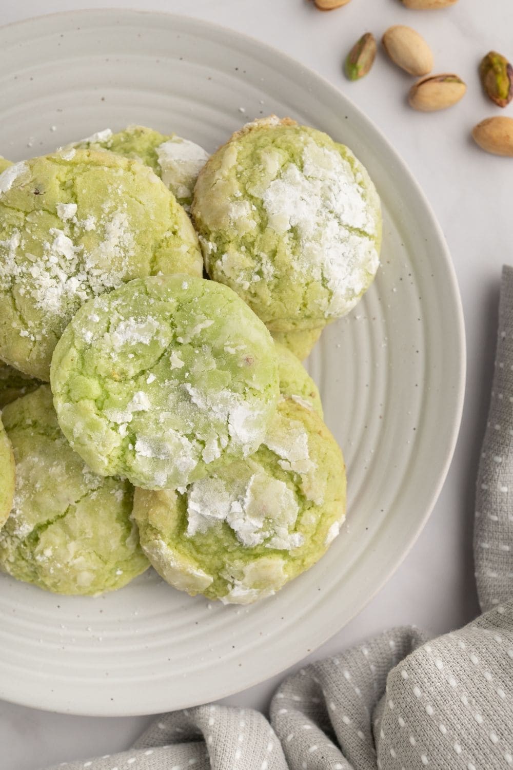 overhead view of a white plate with several homemade pistachio pudding crinkle cookies on it.
