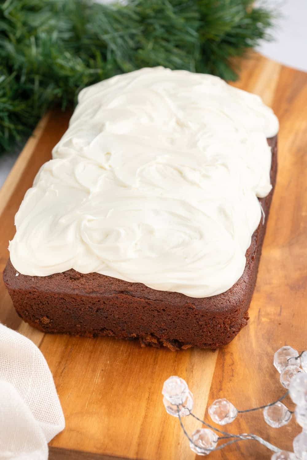 side view of a whole loaf of gingerbread, topped with cream cheese frosting.