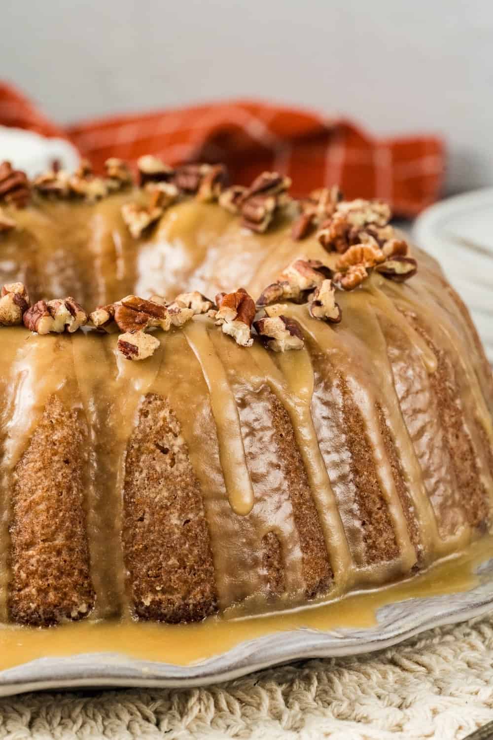 close-up side view of a sweet potato pound cake, topped with a brown sugar glaze that hardens to a satiny finish, along with chopped pecans.
