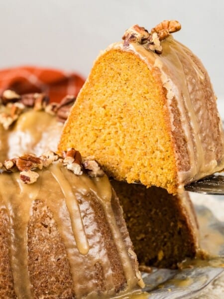 a slice of glazed sweet potato pound cake being lifted off the serving plate by a cake server.