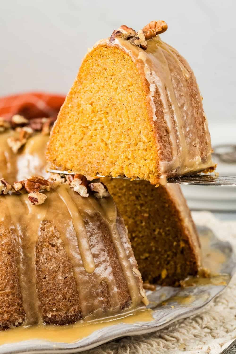 a slice of sweet potato pound cake being lifted from the serving plate, showing the moist interior of the cake.