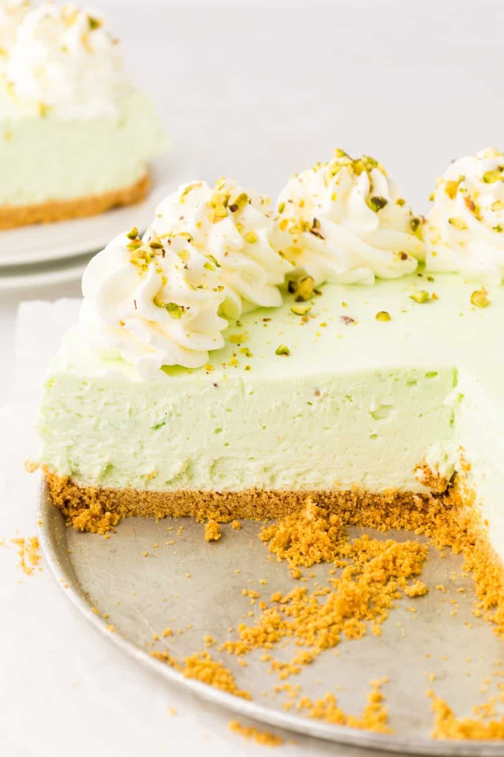 close-up view of sliced no bake pistachio cheesecake, showing the creamy filling atop the graham cracker crust.