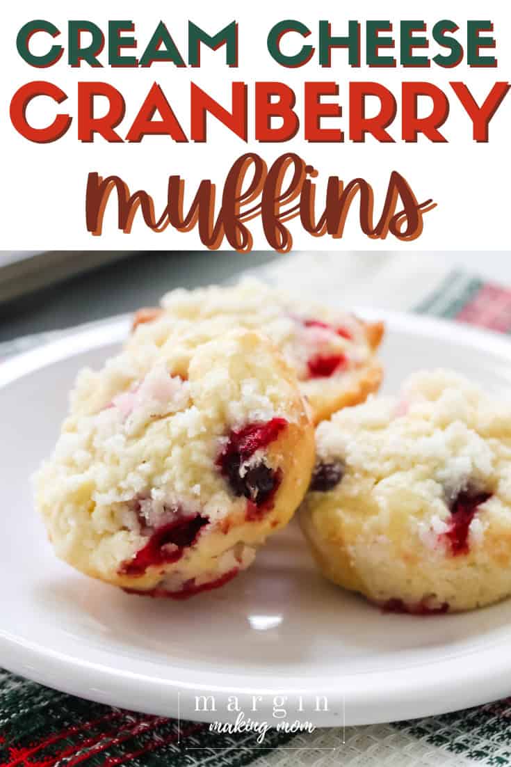 three cream cheese cranberry muffins served on a white plate.
