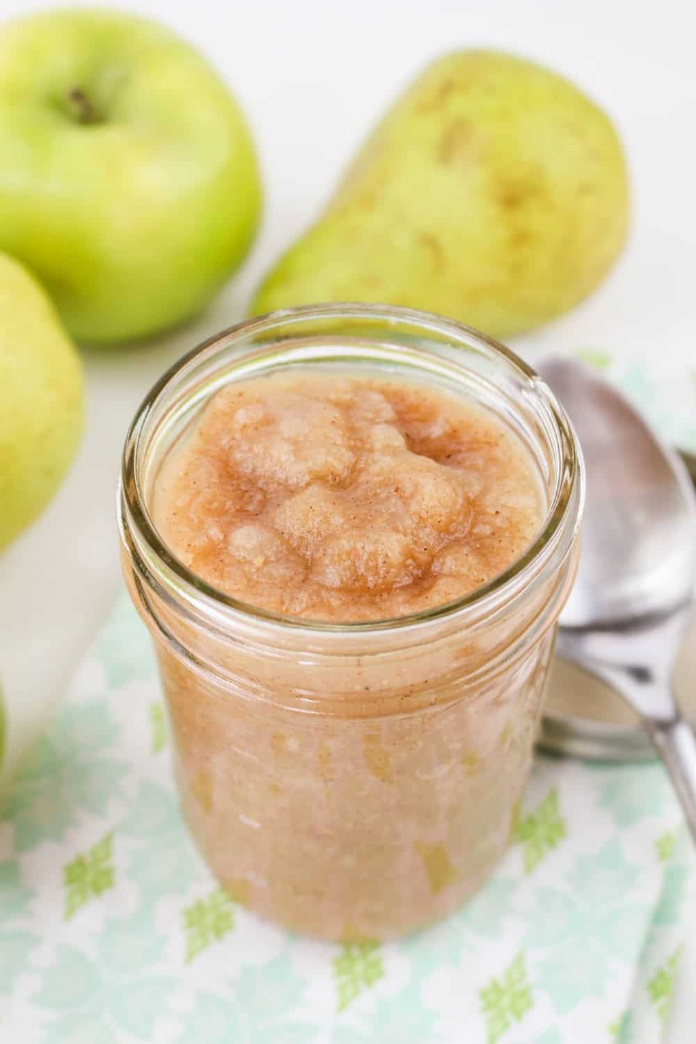 cinnamon apple and pear sauce in a mason jar, with pears and apples in the background.