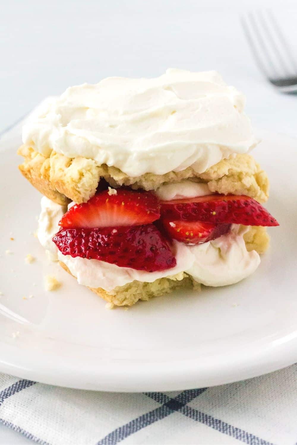 strawberry shortcake, made from scratch, served on a white plate with a fork in the background.