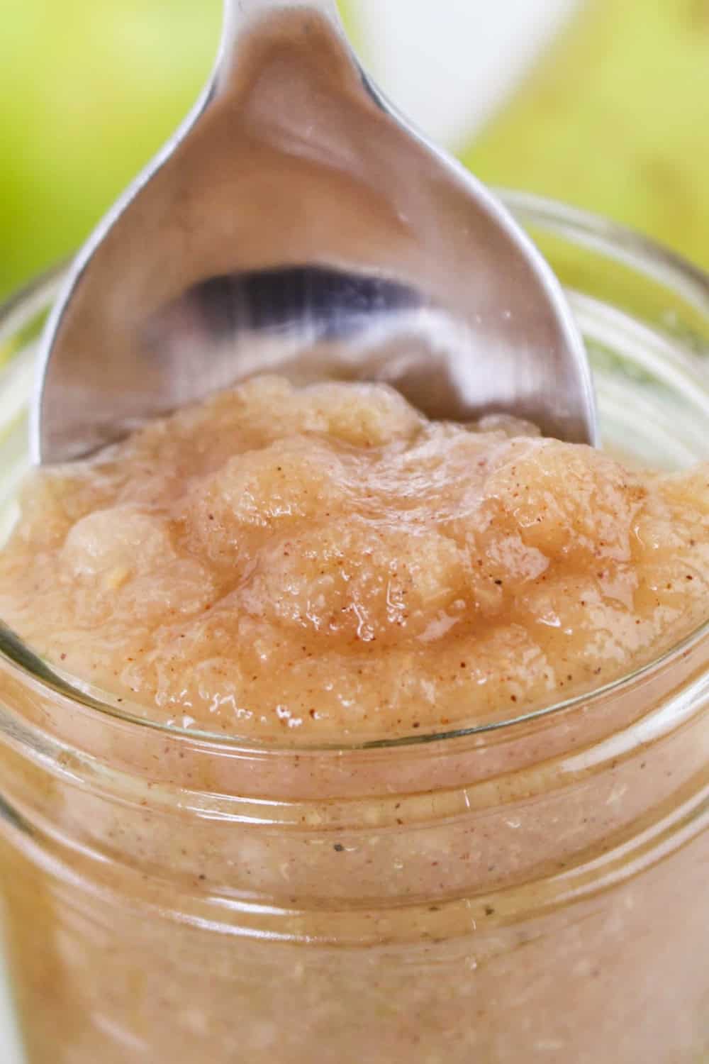 close-up view of a spoon scooping homemade pear applesauce from a jar.