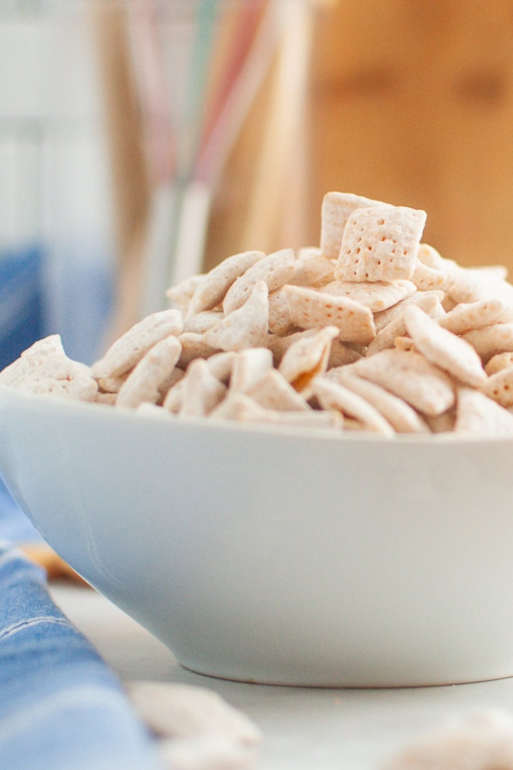 side view of a white bowl filled with banana pudding puppy chow snack mix.