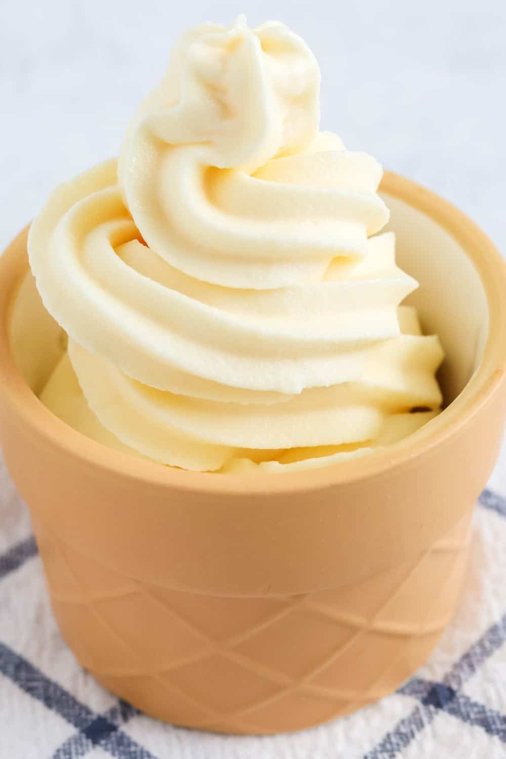Vanilla soft serve that was made in the Ninja Creami soft serve machine, served in a cone-shaped dessert dish.