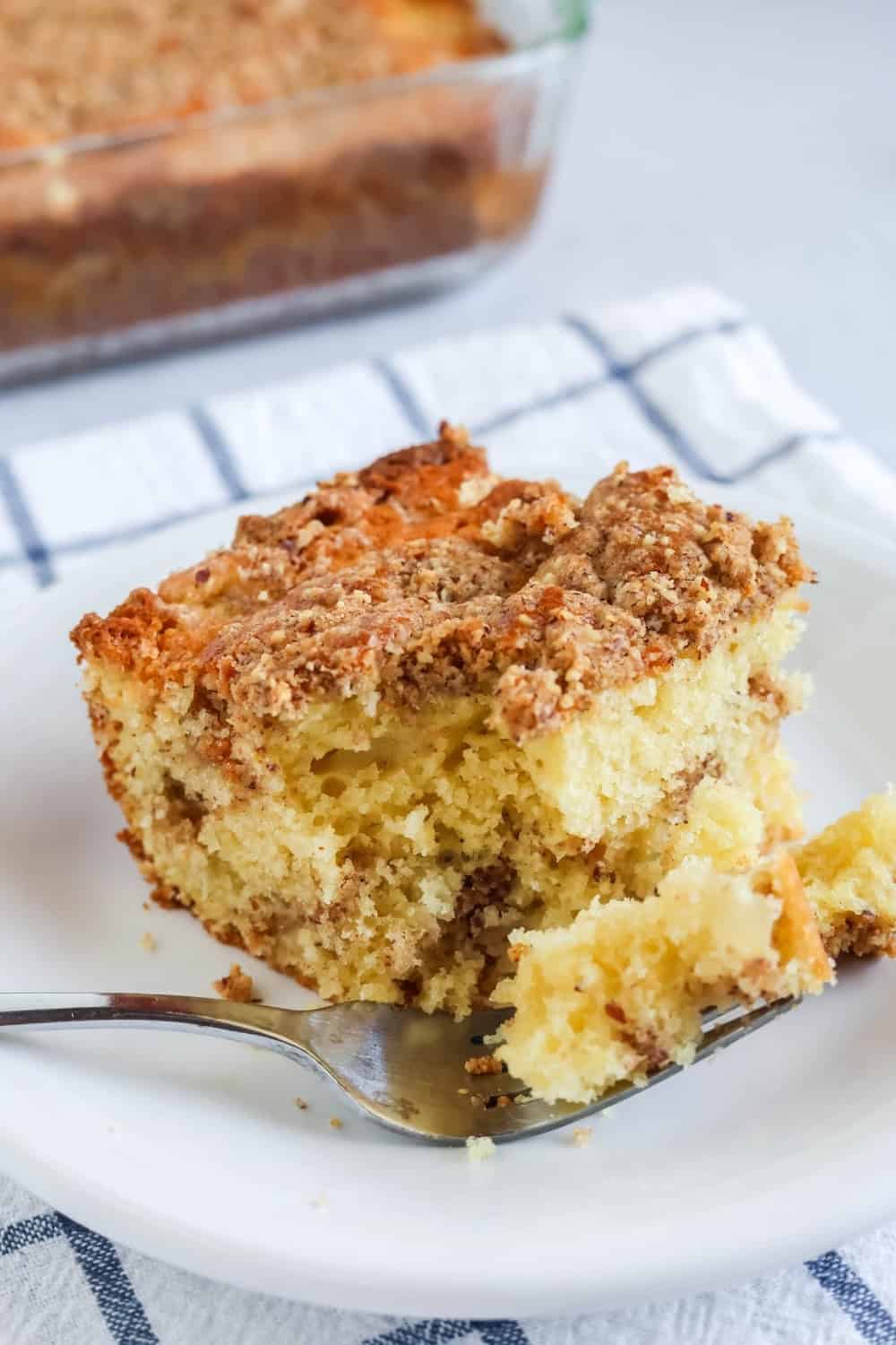 close-up view of pear breakfast cake on a white plate, with a bite taken out of it.