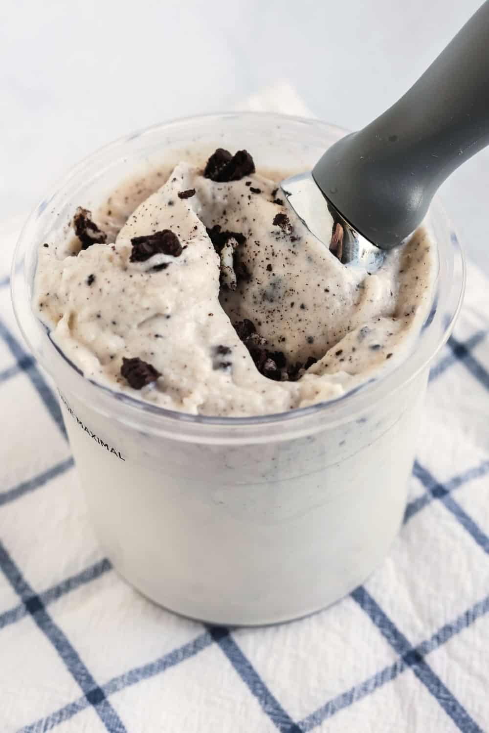 side view of a container of Ninja Creami Oreo frozen yogurt, with an ice cream scoop in the container.