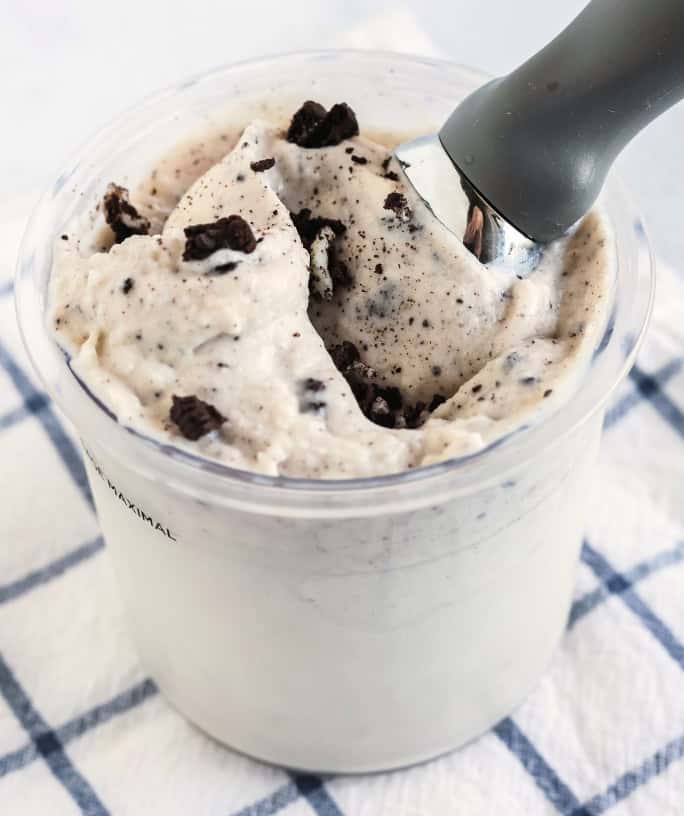 pint of Ninja Creami cookies and cream frozen yogurt with an ice cream scoop in it.