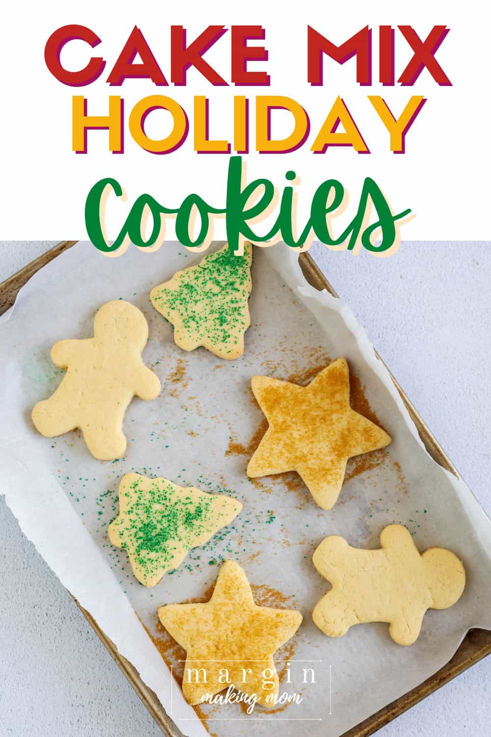 overhead view of a parchment-lined baking sheet with cake mix holiday cookies on it. They're cut into Christmas shapes and some are covered with sprinkles.