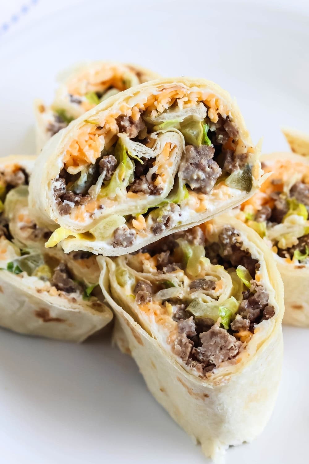 close-up view of the interior of Big Mac inspired cold pinwheels, including cheese, ground beef, lettuce, pickles, and Big Mac sauce.