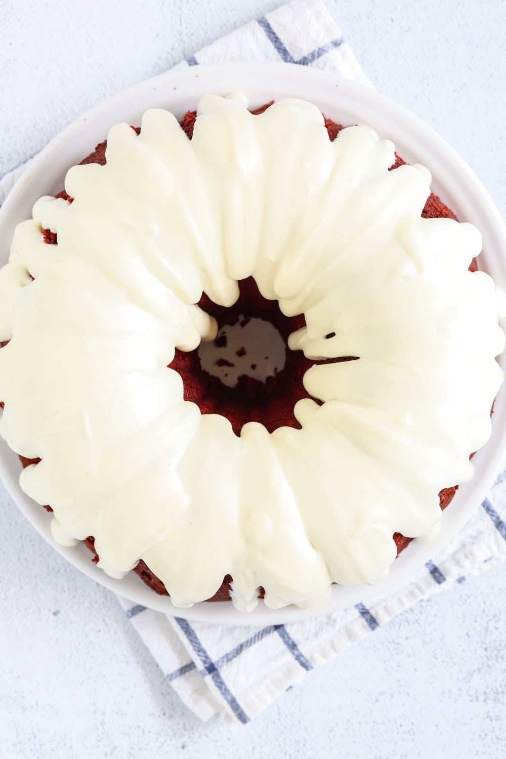 overhead view of red velvet pound cake bundt, topped with cream cheese icing, served on a white plate.