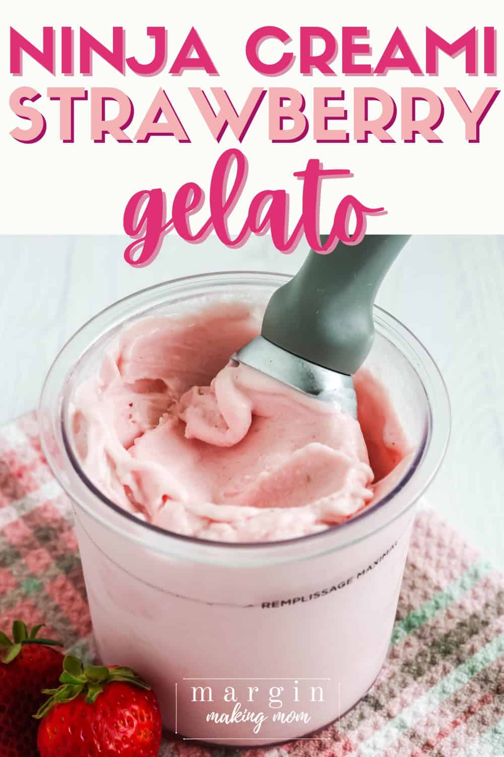 pint of Ninja Creami strawberry gelato with an ice cream scoop in it, and two fresh strawberries next to it.