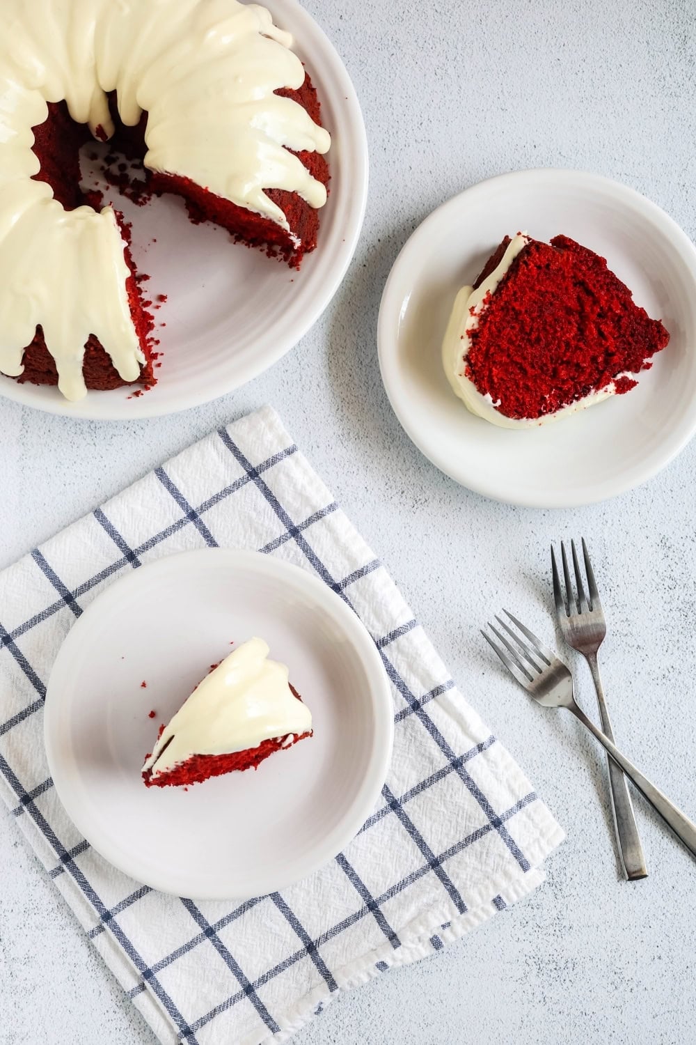 overhead view of two slices of red velvet pound cake, made with a cake mix, on white plates. The remainder of the bundt cake is next to them, along with two forks.